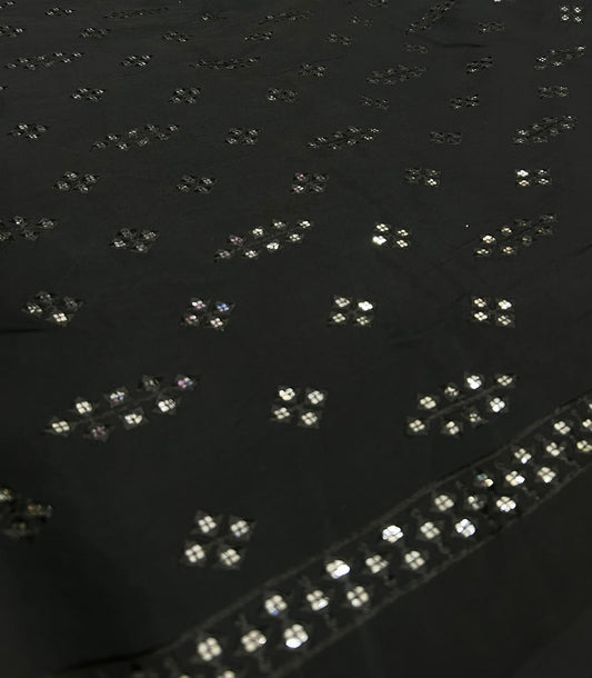 Black fabric with embedded silver sequins on a dark background
