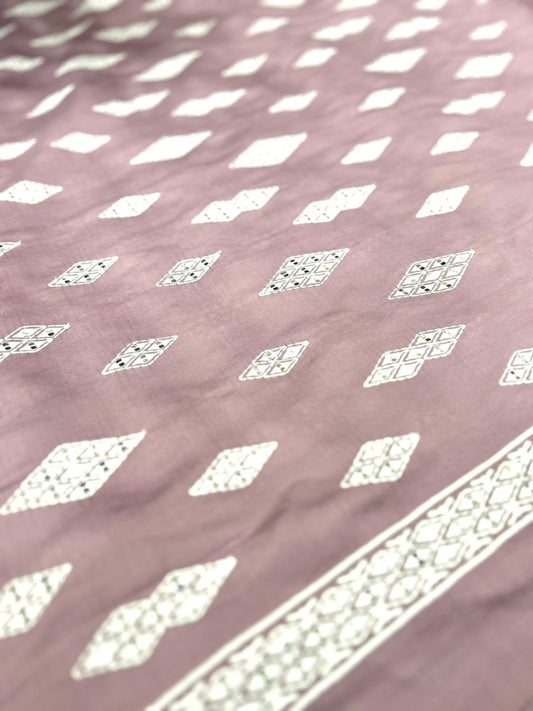 Patterned fabric with white geometric designs on a pink background.
