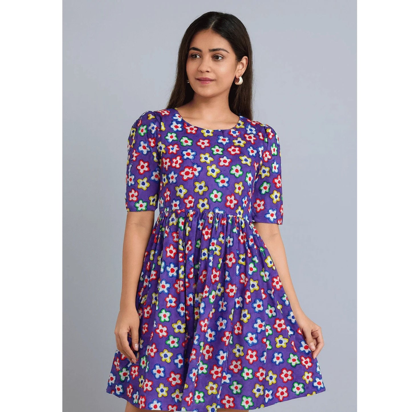 Woman wearing a premium Purple Multicolor Floral Hakoba Cotton Fabric dress featuring vibrant colorful floral print on soft breathable cotton. Ideal for modern dresses, kurtis, tops, tunics, kidswear and casual summer outfits.