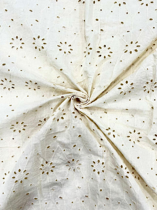 Close-up of dyeable ecru cotton textile featuring all-over flower motifs, perfect for making dreamy summer outfits and apparel.
