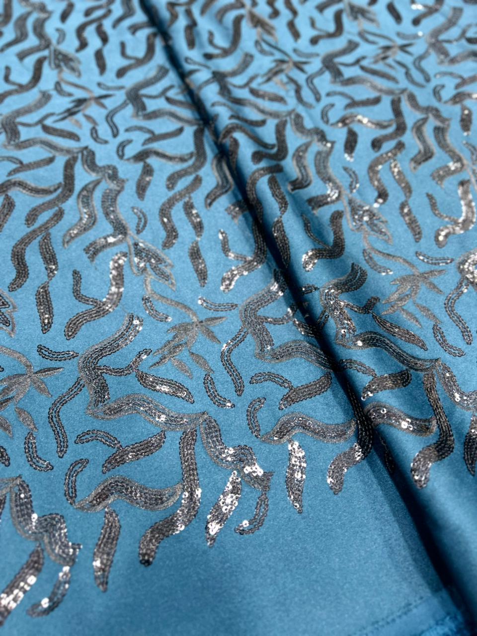 Azure blue TR satin fabric with heavy silver sequin embroidery in abstract flowing patterns, ideal for koti, blazer and Indo-western outfits.