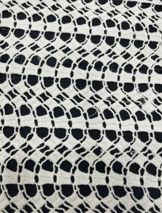 White dyeable GPO cotton guipure lace fabric with wavy geometric cutwork pattern.