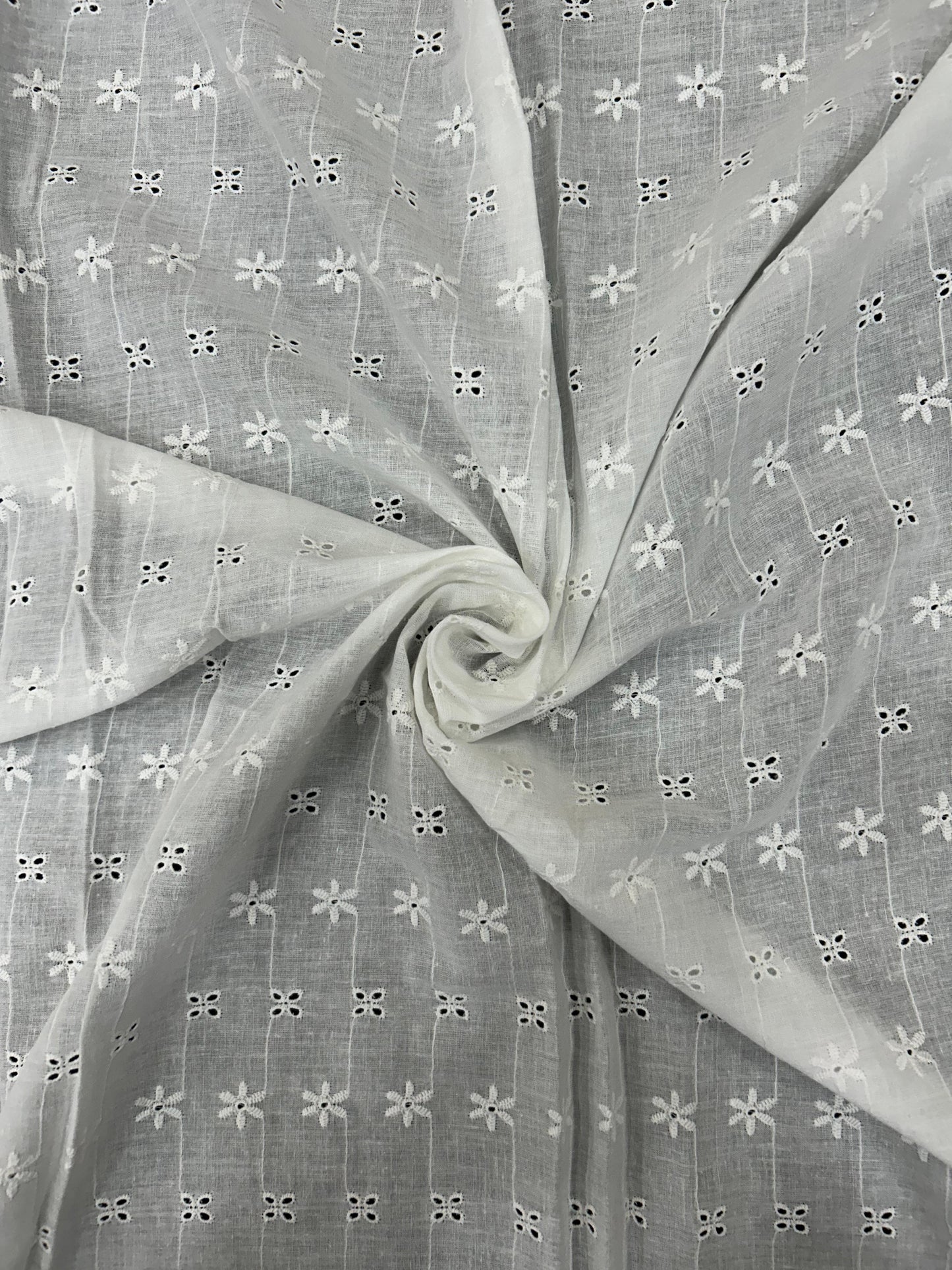 Premium White Hakoba Schiffli Cotton Fabric, soft and breathable, featuring intricate cutwork embroidery for elegant kurtis and summer outfits.

