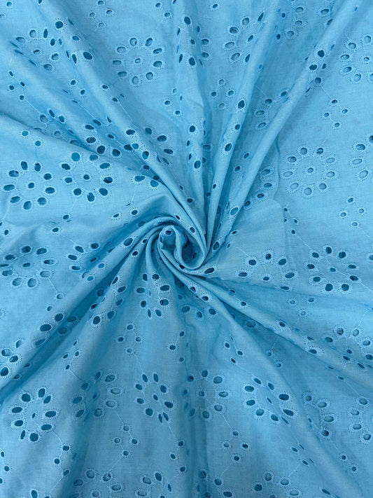 Close-up of soft sky-blue cotton fabric with all-over delicate floral design, great for creating elegant and stylish apparel.