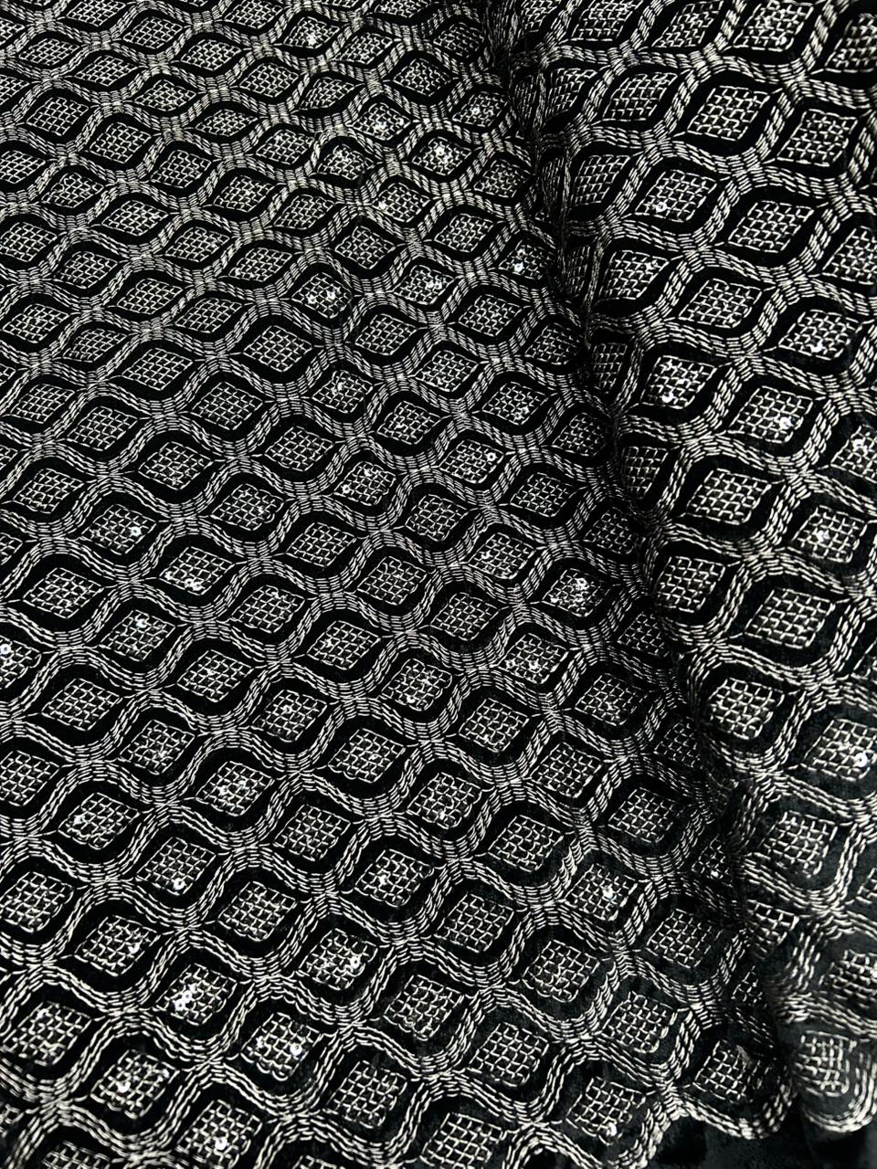 Luxury grey velvet fabric laid flat showcasing dense geometric thread embroidery and sparkling sequin detailing.