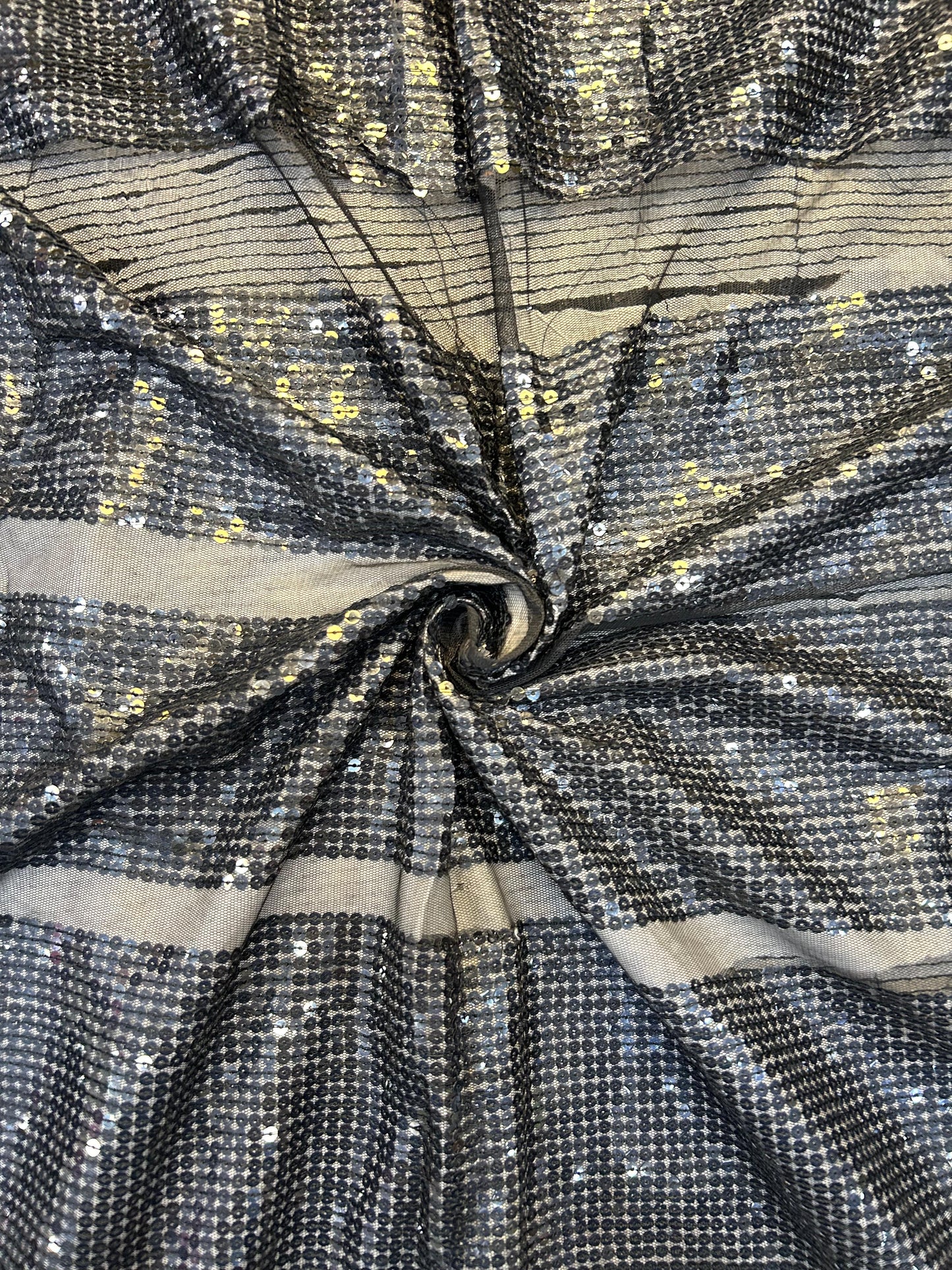 Close-up of shimmering black net textile with intricate gold sequin work, ideal for elegant sarees, anarkalis, and Indo-Western outfits.