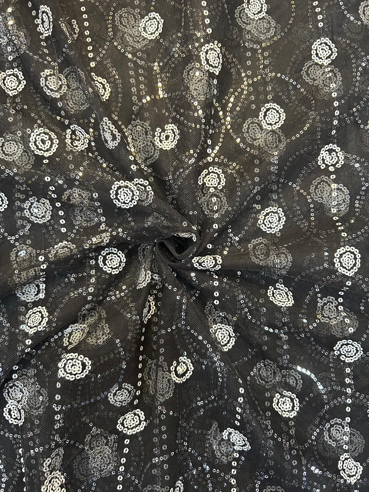 Close-up of dazzling black net textile with shimmering white sequin work, ideal for elegant sarees, anarkalis, and festive party wear outfits.