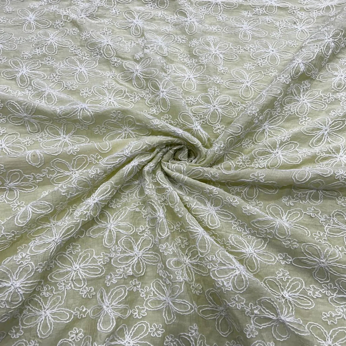 Close-up of pastel green Mal Chanderi fabric with white floral embroidery, soft lightweight cotton fabric for kurti, salwar suit, ethnic wear, dresses and designer apparel making.