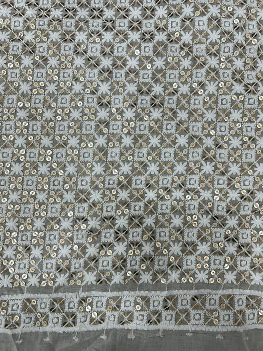 Textured fabric with geometric pattern and sequins on a gray background.