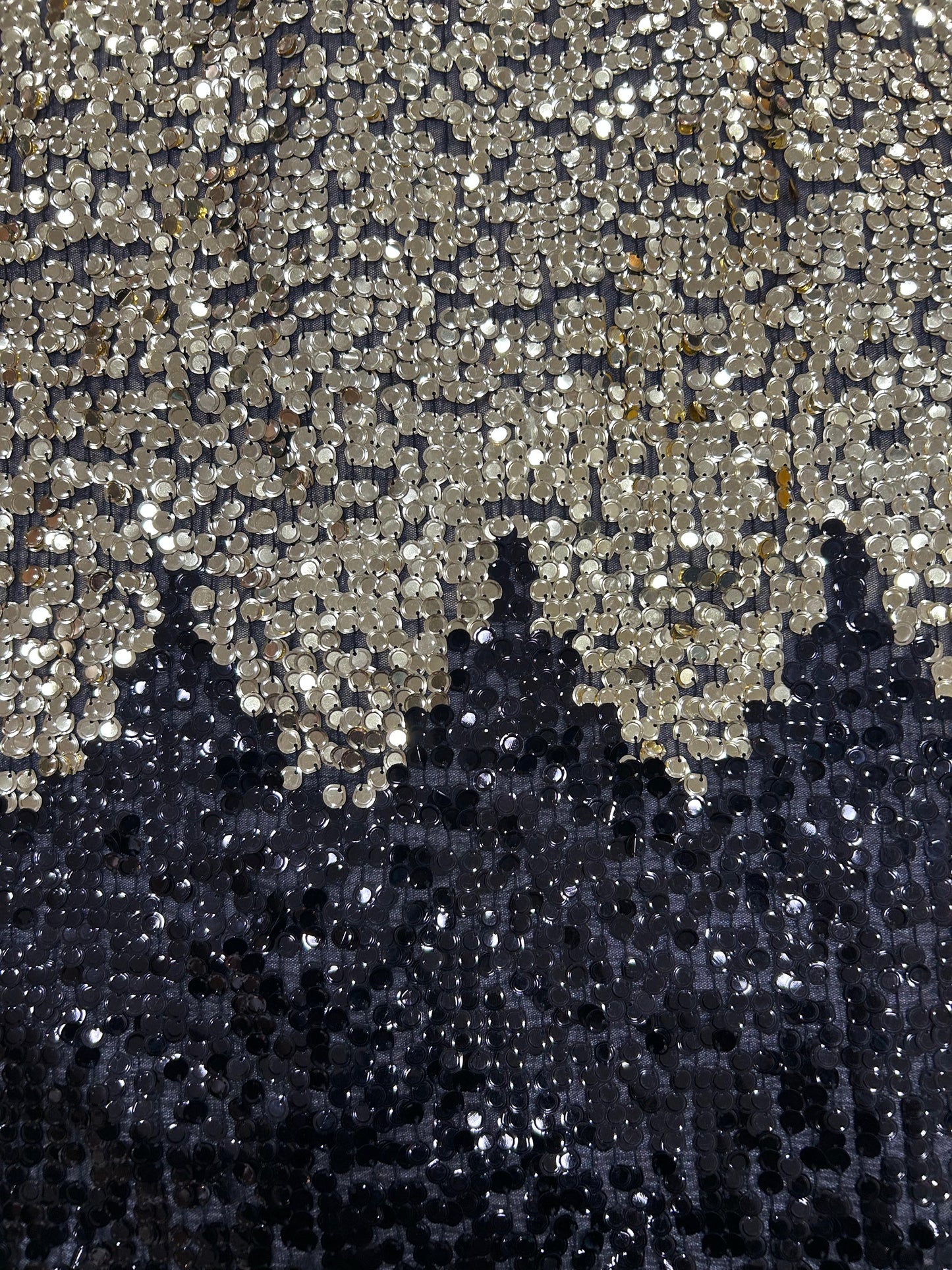 Close-up of dazzling black net textile with two-toned gold and black sequins, creating a shimmering, shifting effect for designer party wear.