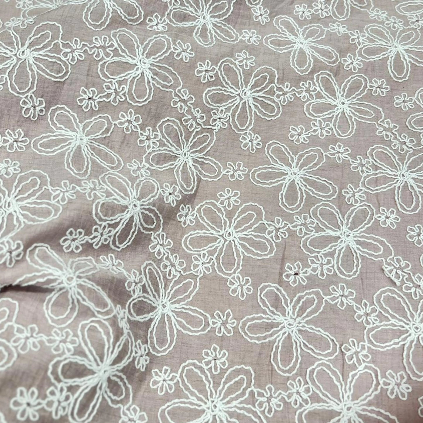 Close-up of blush pink Mal Chanderi fabric featuring white floral embroidery, 55-inch width and 49-inch embroidered work.