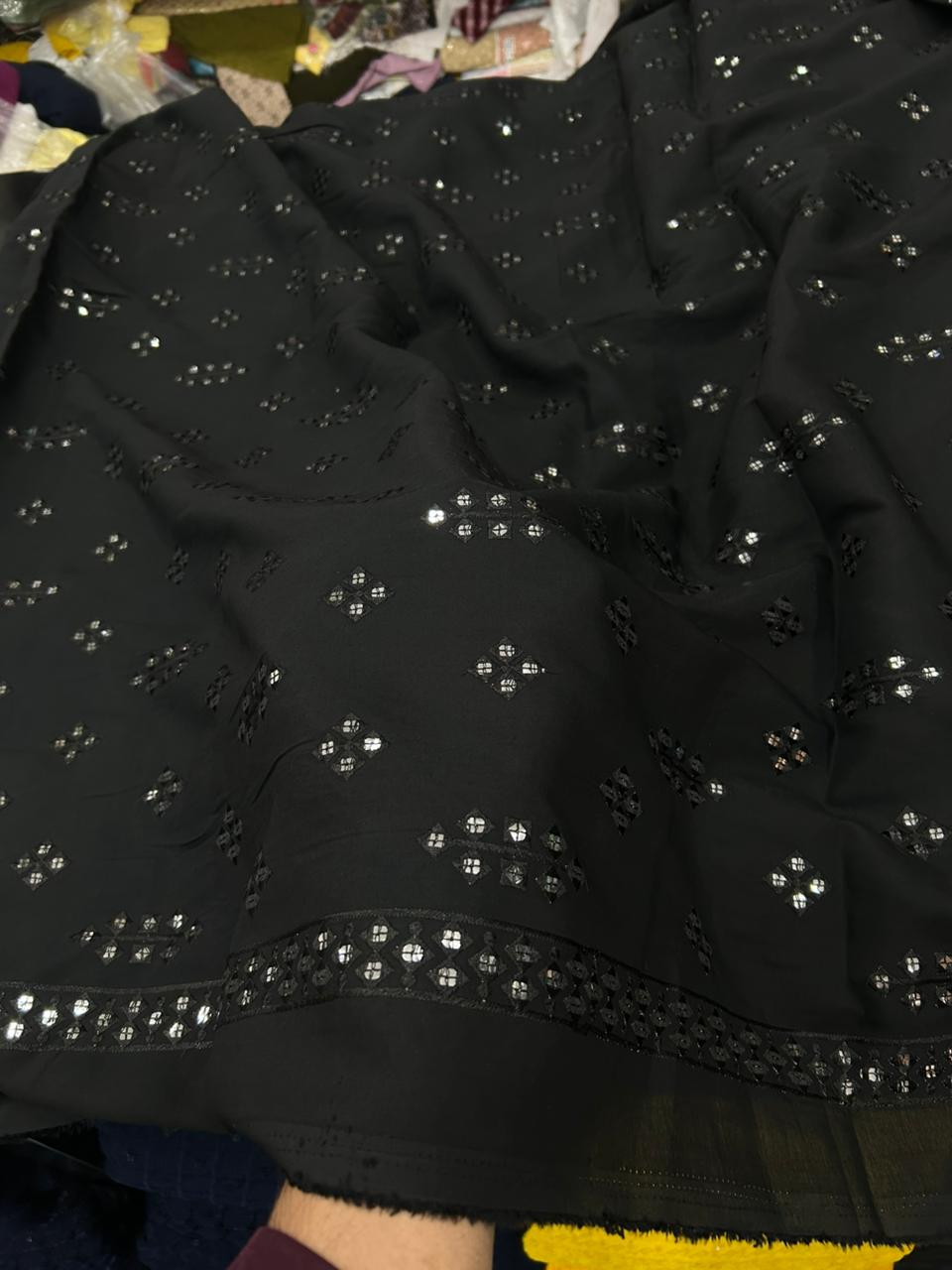 Black garment with star-shaped embellishments on a textured surface