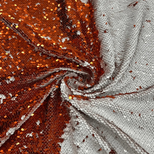 Luxury orange and silver magic reversible sequin mesh fabric with two-way flip sequins on soft net, ideal for bridal gowns, cocktail dresses, stage costumes, lehengas, bags, cushions and DIY crafts.