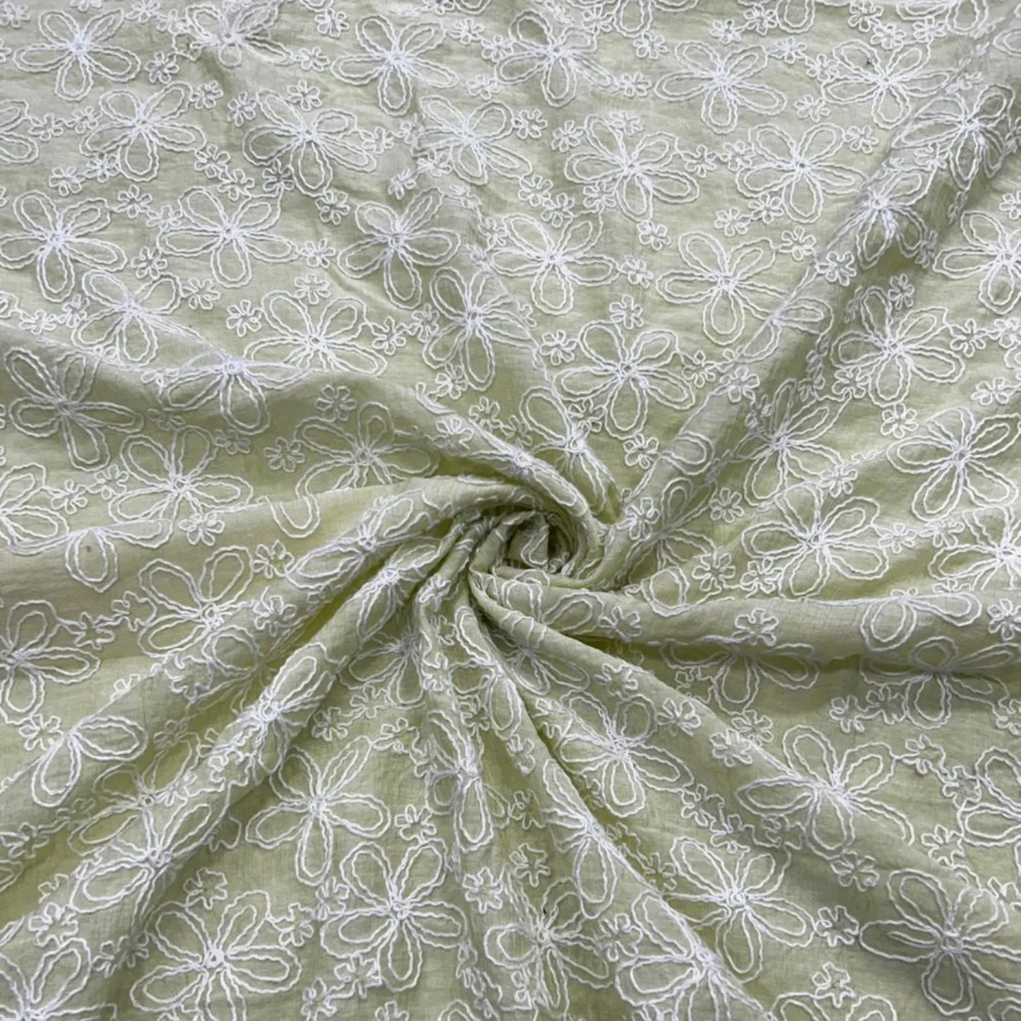 Close-up of Pastel Green Mal Chanderi fabric with white floral embroidery.