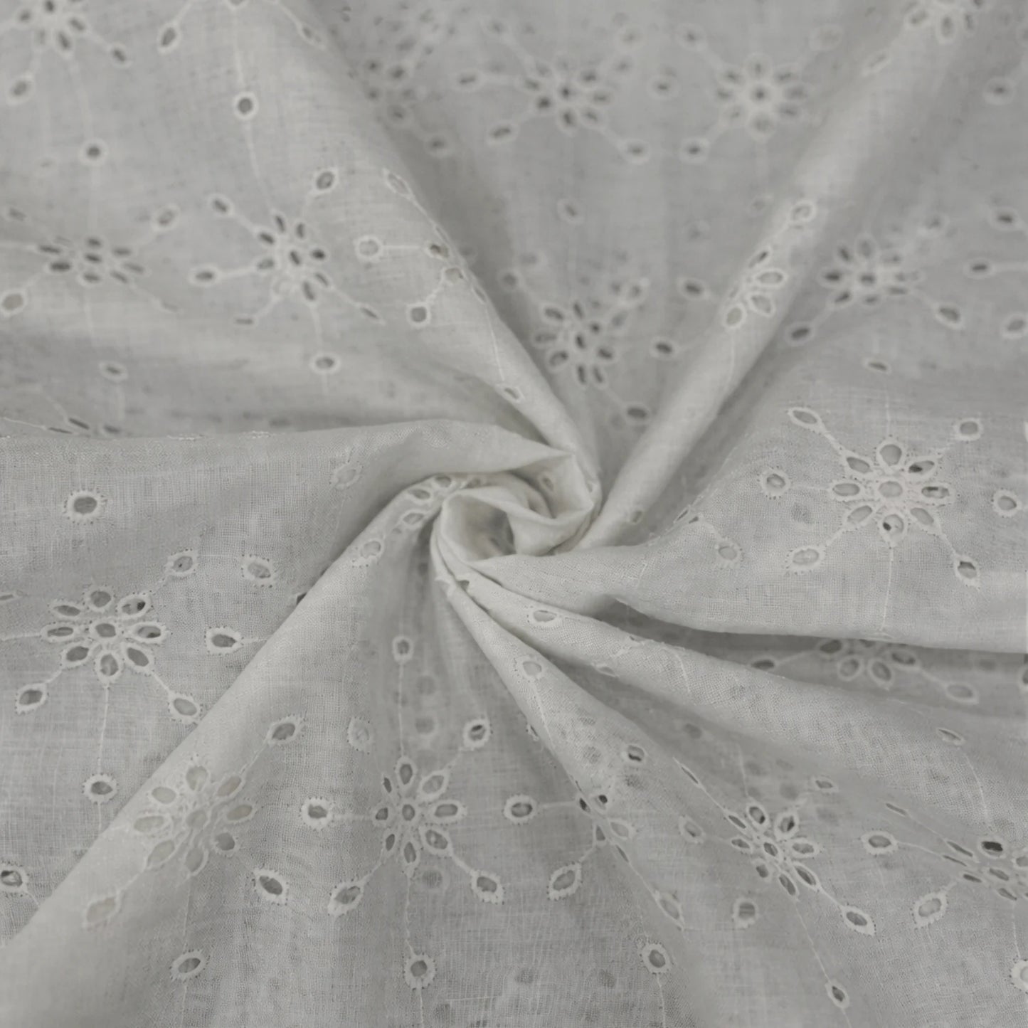 Premium White Hakoba Schiffli Cotton Fabric featuring elegant geometric floral eyelet embroidery. Soft breathable cotton fabric with intricate all-over embroidery, 56 inch width, ideal for kurtis, dresses, tops, co-ord sets, kidswear and ethnic wear.